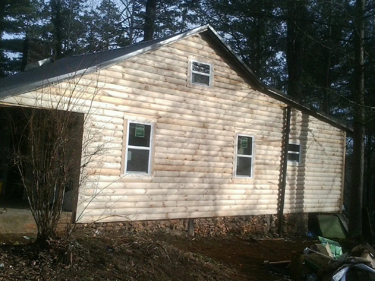 New log siding and dark metal roofing on a gable end in Trade