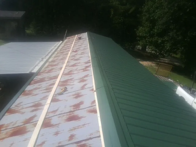 Old rusted panels beside newly installed green metal roofing — Wind Damage Roof Repair by Roofing Brothers in Trade