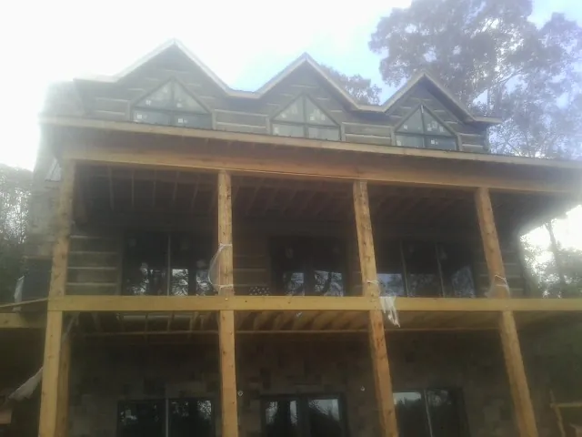 Dormers and porch framing on a large log home under construction — Roof Coating work by our crew in Trade