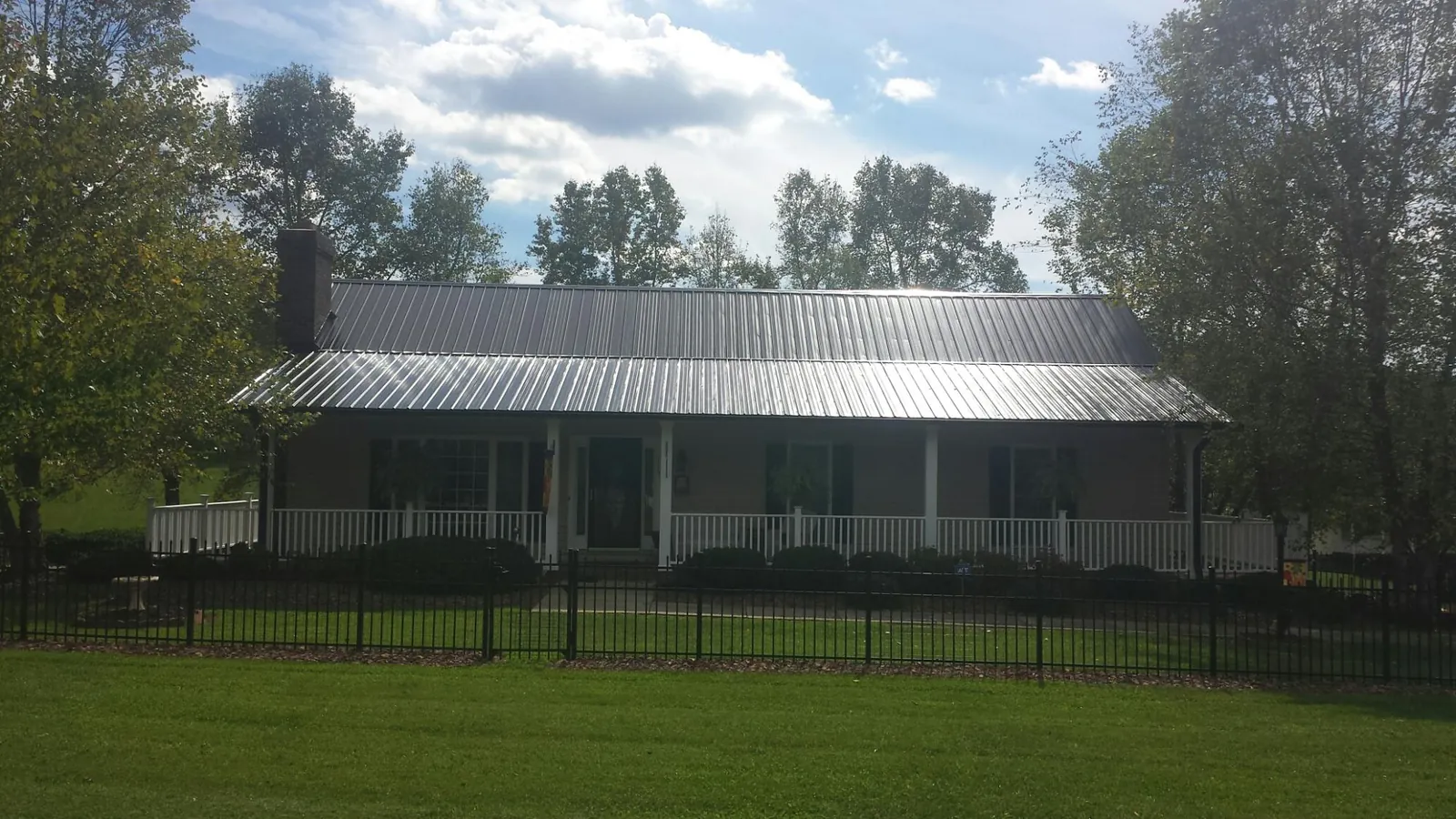 Gray metal roof on a brick ranch with a full width front porch — Gutter Guard Installation work by our crew in Trade