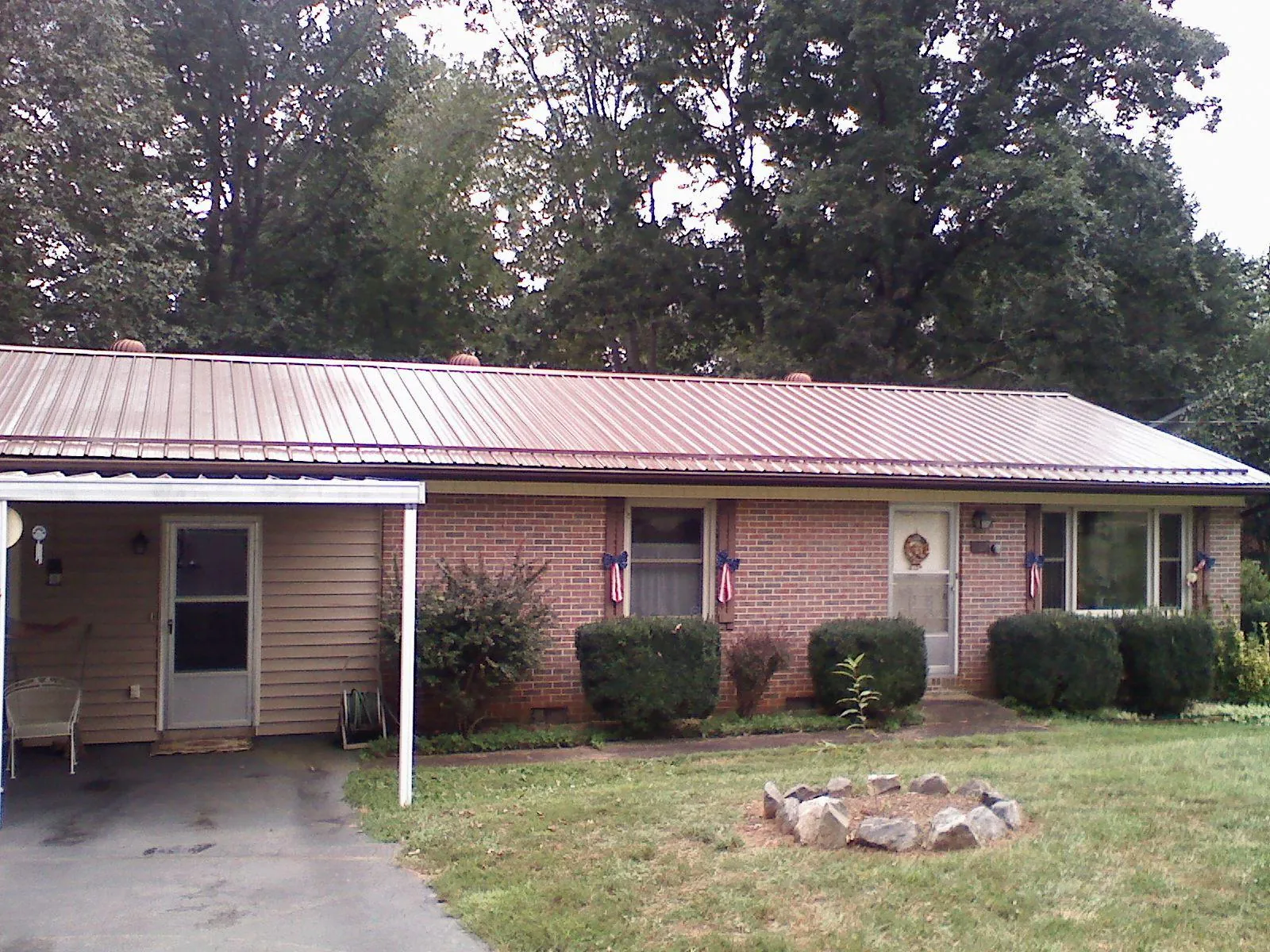 Bronze metal roof and carport on a brick ranch home — Roof Repair work by our crew in Trade