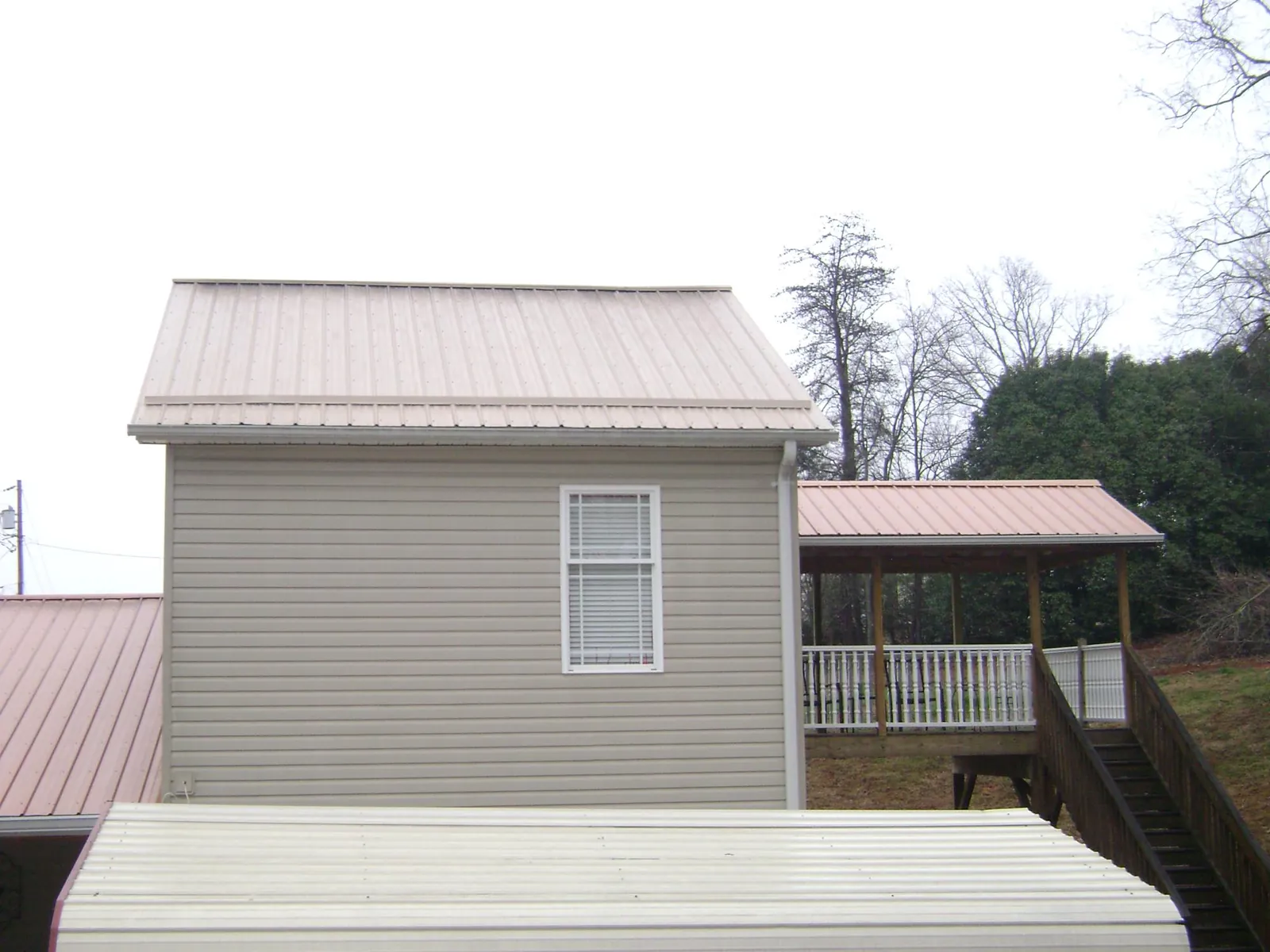 Tan metal roofs on a two story addition and attached porch, from a Roof Replacement job in Trade